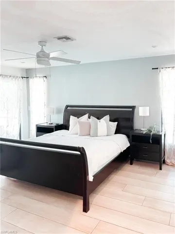 Bedroom featuring light hardwood / wood-style floors, ceiling fan, and multiple windows