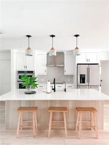 Kitchen with an island with sink, tasteful backsplash, a kitchen bar, and stainless steel appliances