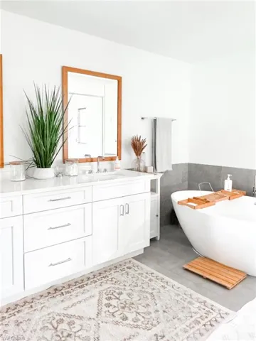 Bathroom with tile walls, tile floors, and double sink vanity