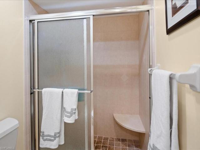 Tiled shower with glass doors and comfort level toilet.