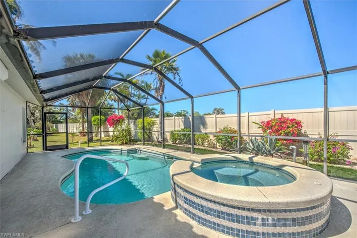 View of pool with a patio area, a fenced backyard, a pool with connected hot tub, and a lanai