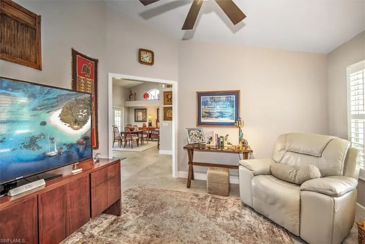 Living room with vaulted ceiling, baseboards, and ceiling fan