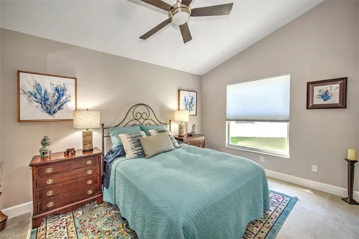 Bedroom featuring a ceiling fan, baseboards, and vaulted ceiling