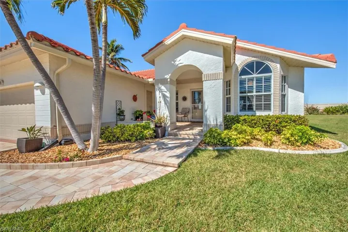 Mediterranean / spanish-style house with stucco siding, a front yard, an attached garage, and a tile roof
