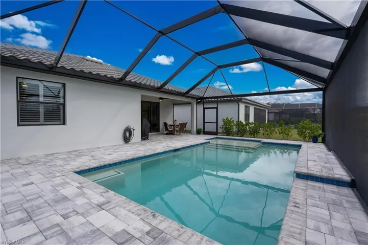 View of pool featuring a patio and glass enclosure