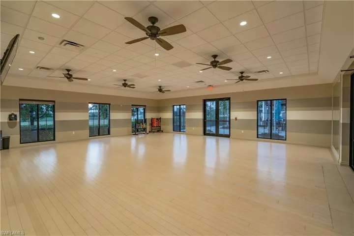 Empty room featuring light hardwood / wood-style floors, a drop ceiling, a raised ceiling, and ceiling fan