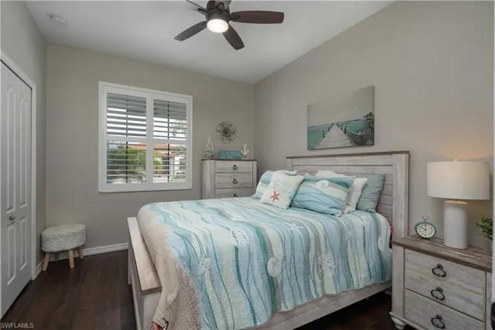 Bedroom with ceiling fan, dark hardwood / wood-style flooring, and a closet