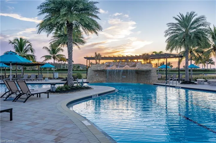 Pool at dusk featuring a patio and pool water feature