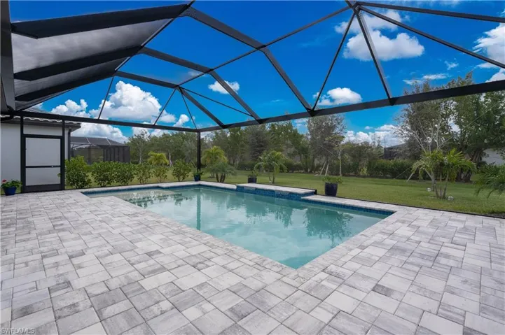 View of pool with glass enclosure, a patio area, and a yard