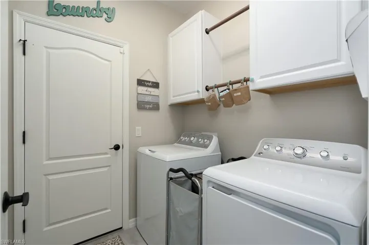 Laundry room featuring light tile patterned floors, washer and clothes dryer, and cabinets