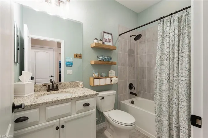 Full bathroom featuring shower / bath combination with curtain, toilet, and vanity