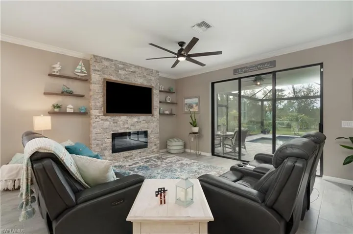 Living room with a fireplace, ornamental molding, and ceiling fan