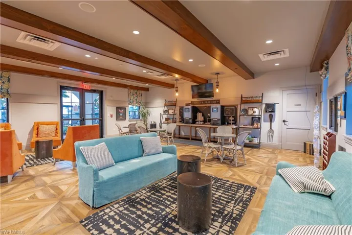 Living room featuring light parquet floors, beam ceiling, and french doors