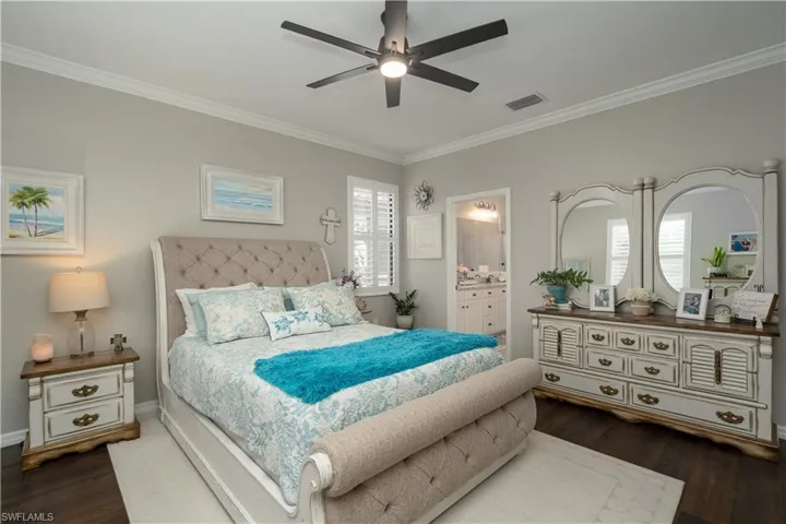 Bedroom with dark hardwood / wood-style flooring, ensuite bathroom, ceiling fan, and crown molding