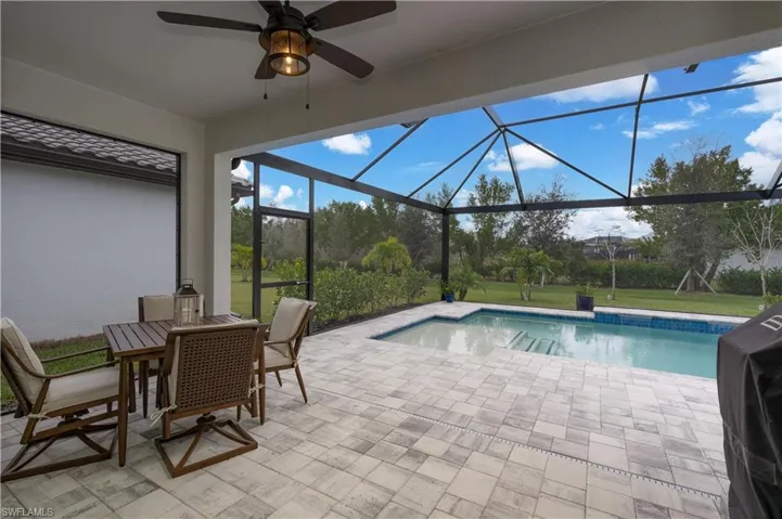 View of pool featuring a patio area, ceiling fan, and glass enclosure