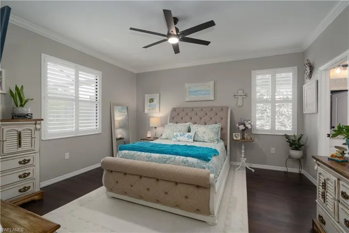 Bedroom with ornamental molding, ceiling fan, and dark wood-type flooring