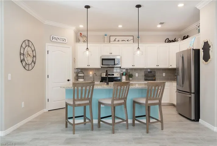 Kitchen with tasteful backsplash, stainless steel appliances, pendant lighting, an island with sink, and light stone countertops