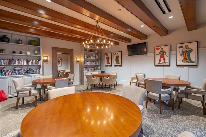 Carpeted dining room featuring beamed ceiling, built in features, and a chandelier