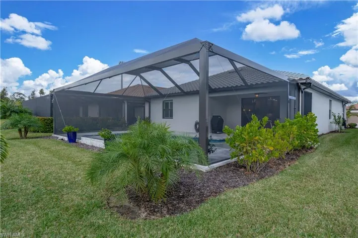 Rear view of house with a lanai and a lawn