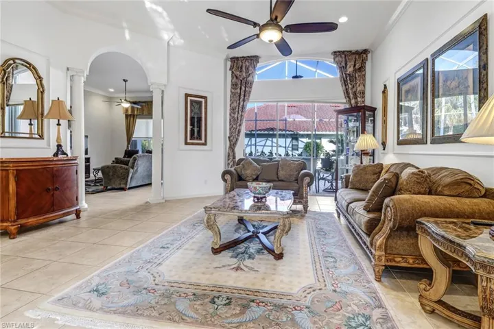 Living room with tile flooring, ceiling fan, and decorative columns