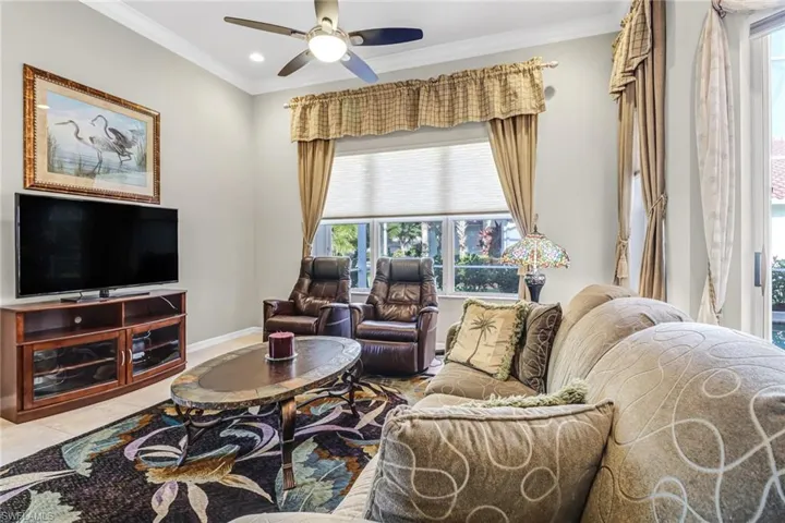 Tiled living room featuring ornamental molding and ceiling fan