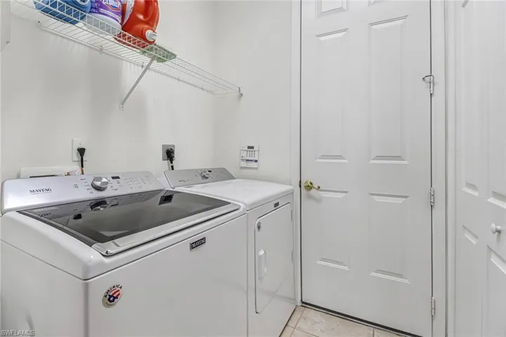 Laundry room with electric dryer hookup, washer and clothes dryer, and light tile flooring