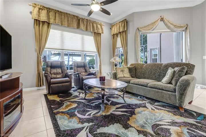 Living room with ornamental molding, ceiling fan, and light tile floors