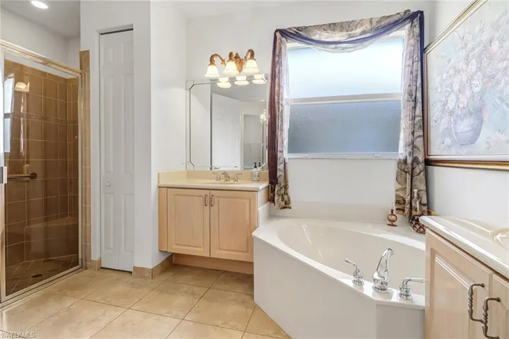 Bathroom featuring tile flooring, large vanity, and plus walk in shower