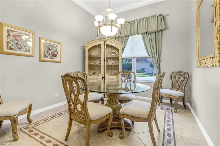 Tiled dining room with a chandelier and crown molding