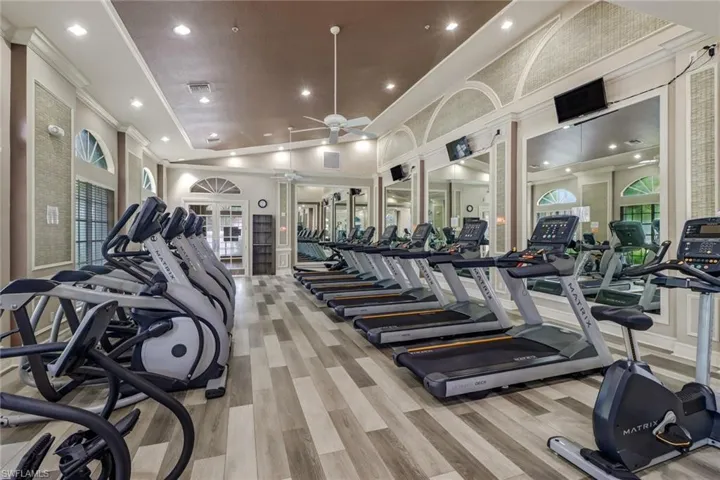 Gym with ornate columns, ceiling fan, plenty of natural light, and light hardwood / wood-style floors
