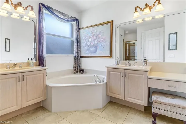 Bathroom with a bath, tile flooring, and dual bowl vanity