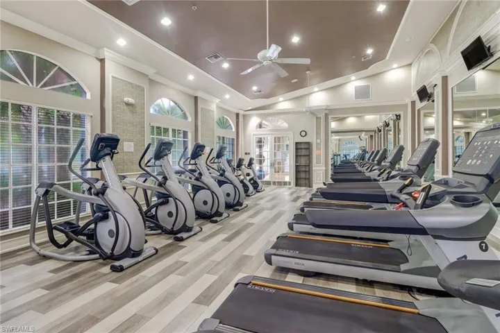 Gym featuring high vaulted ceiling, ornate columns, ceiling fan, and light hardwood / wood-style flooring