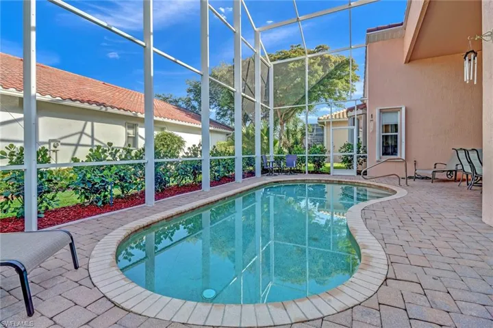 View of swimming pool featuring glass enclosure and a patio area