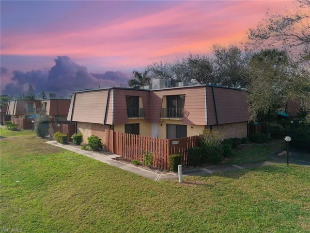 Back of property at dusk featuring mansard roof