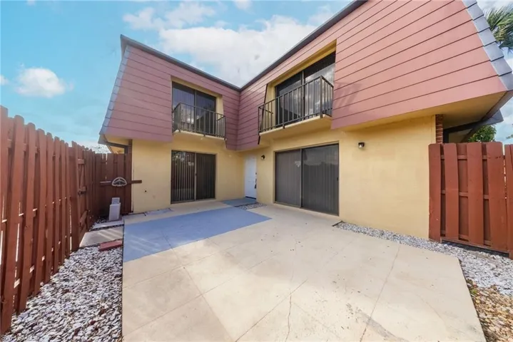 Rear view of house with a balcony, stucco siding, a patio, and a gate