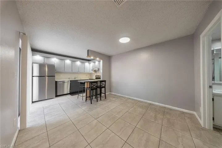 Kitchen featuring stainless steel appliances, a textured ceiling, light tile patterned floors, light countertops, and gray cabinets