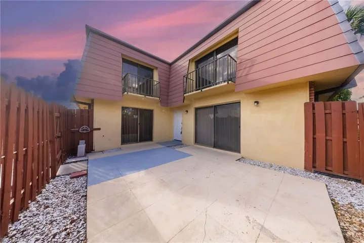 Back of property with a balcony, stucco siding, a patio, and a gate