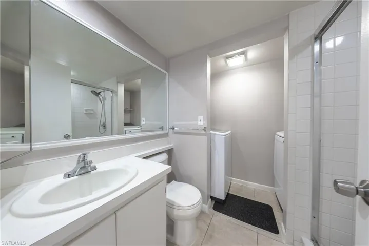 Bathroom with vanity, a stall shower, light tile patterned floors, and independent washer and dryer