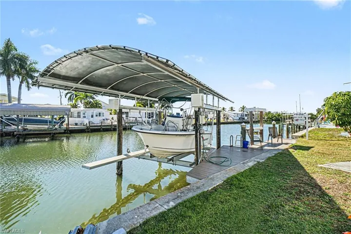 Dock area featuring boat lift, a water view, and a lawn