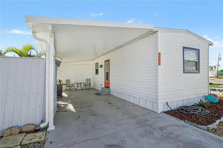 View of property exterior with a carport, entry steps, and a patio area