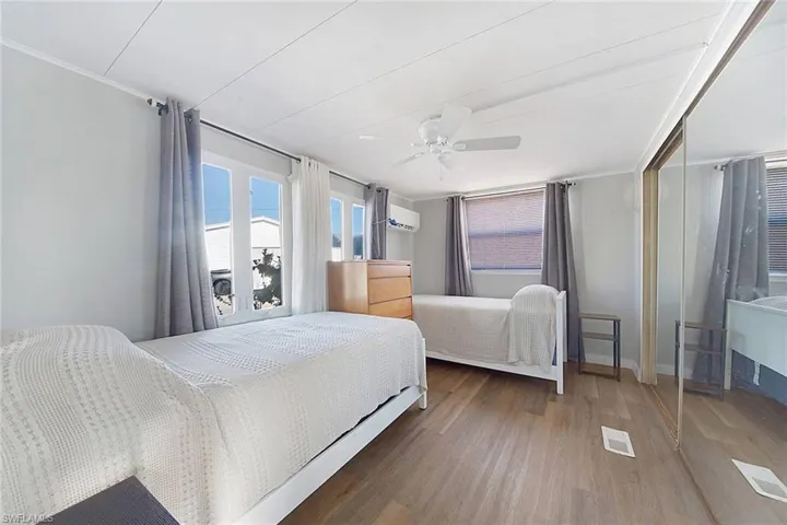 Bedroom with dark hardwood / wood-style flooring, an AC wall unit, and ceiling fan
