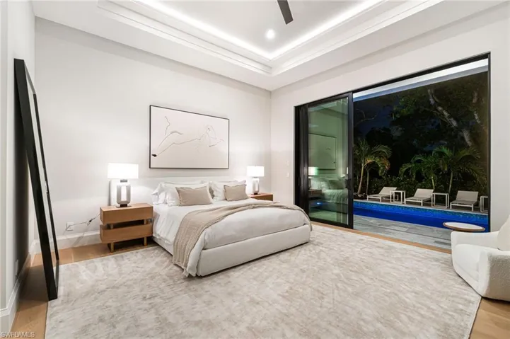 Bedroom with hardwood / wood-style floors, ceiling fan, and a raised ceiling