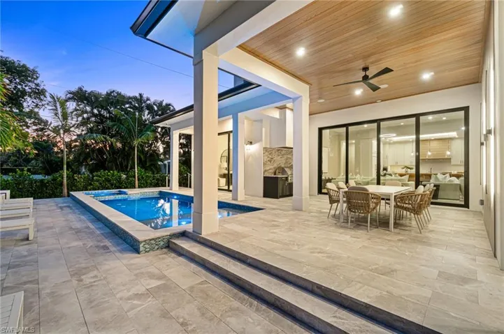 Pool at dusk with ceiling fan, a jacuzzi, and a patio area