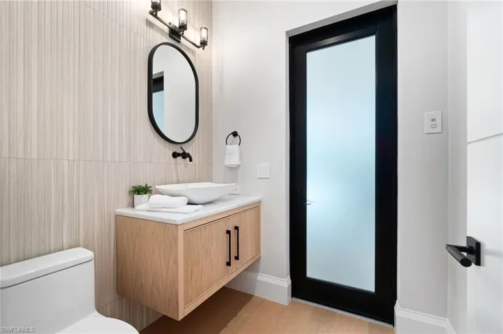 Bathroom with wood-type flooring, vanity, toilet, and tile walls