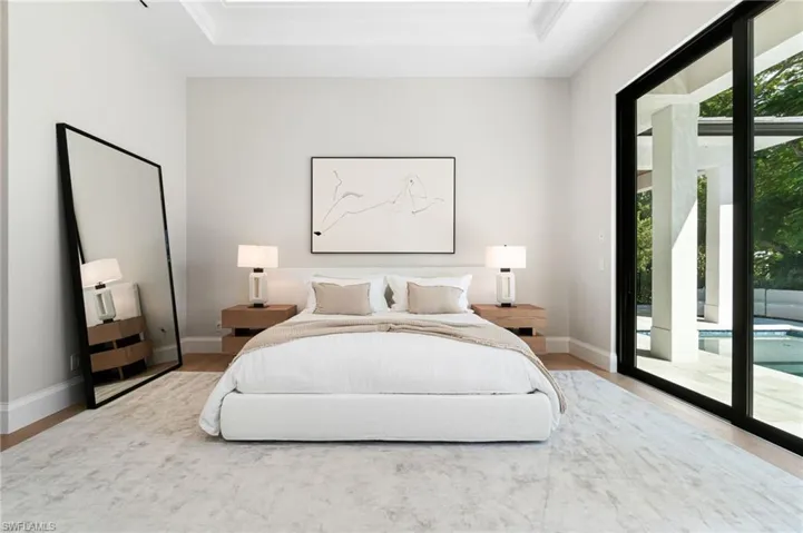 Bedroom featuring access to exterior, wood-type flooring, and a raised ceiling