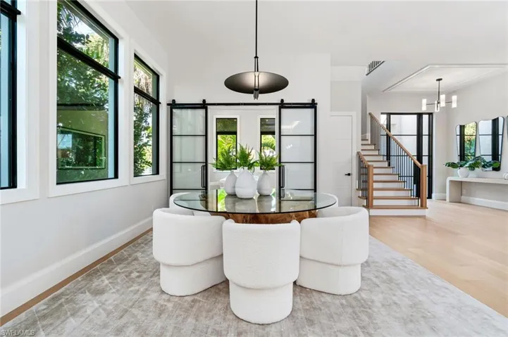 Dining room featuring light hardwood / wood-style floors, plenty of natural light, a notable chandelier, and a barn door