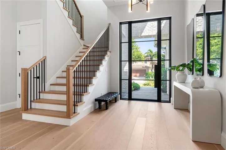 Entryway with a chandelier, light hardwood / wood-style floors, and a towering ceiling