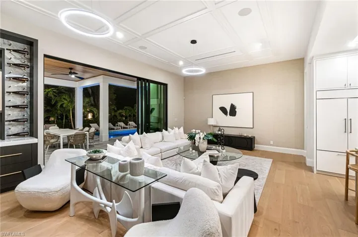 Living room with light hardwood / wood-style floors, ceiling fan, and coffered ceiling