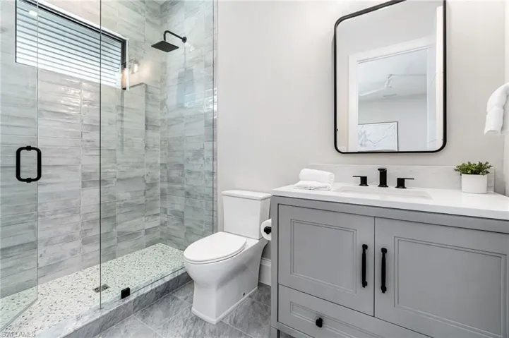 Bathroom with toilet, vanity, and an enclosed shower