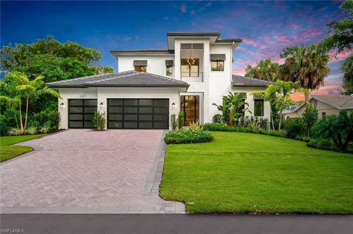 View of front of property featuring a garage and a yard